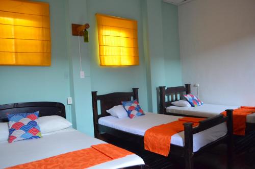 a room with three beds with orange and blue walls at Casona Don Juan Hostel in San Gil