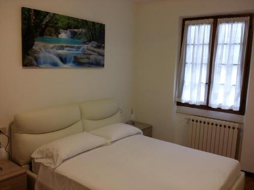 sypialnia z białym łóżkiem i obrazem na ścianie w obiekcie Villa Panoramica w Tremosine Sul Garda