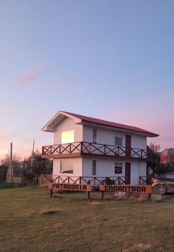 a white house with a sign in front of it at Cabañas Patagonia Encantada in Puerto Natales