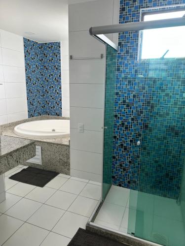 a bathroom with a shower with a sink and a tub at Cobertura Sol Sereno in Cabo Frio