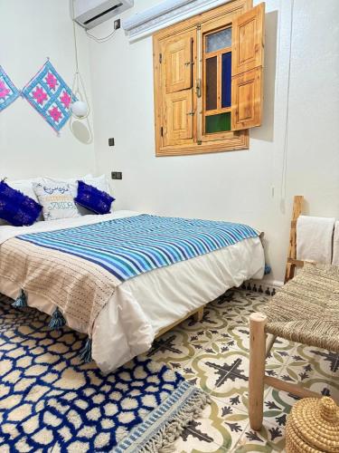 a bedroom with a bed and a window and a rug at Gite Marbie maison rurale, une expérience naturelle unique, au coeur du moyen atlas, Maroc in Kasba Tibouda