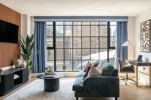 a living room with a couch and a large window at The Spitalfields Works by Urban Rest in London