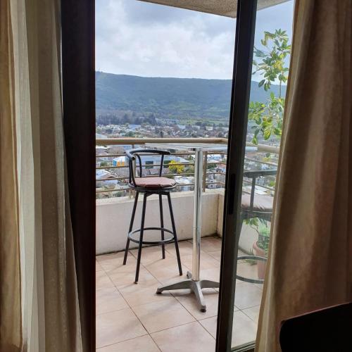 a stool on a balcony with a view of a city at Departamento Alameda Talca in Talca