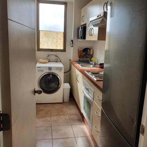 a small kitchen with a washing machine and a window at Departamento Alameda Talca in Talca