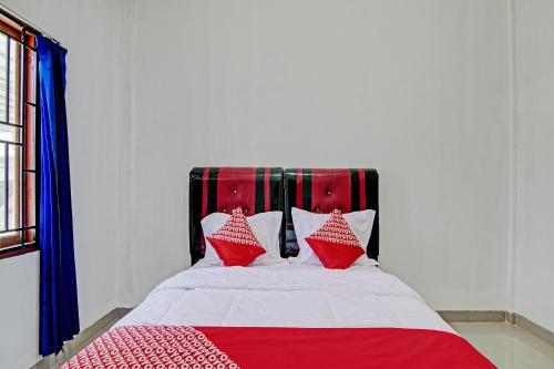 a bed with red and white pillows on it at Hotel O Lestari Baru Syariah Near SMA Negeri 1 Salo in Bangkinang