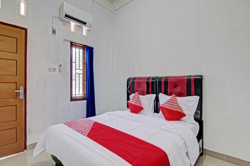 a bedroom with a red and white bed with red pillows at Hotel O Lestari Baru Syariah Near SMA Negeri 1 Salo in Bangkinang