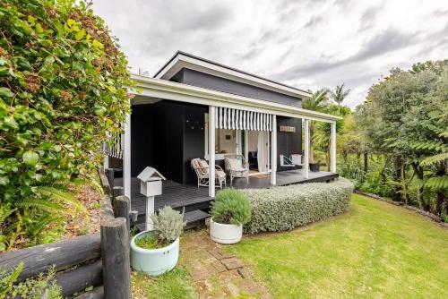 a small house with a deck and a yard at Rosies cottage hideaway in Stanmore Bay with lovely seaview in Whangaparaoa