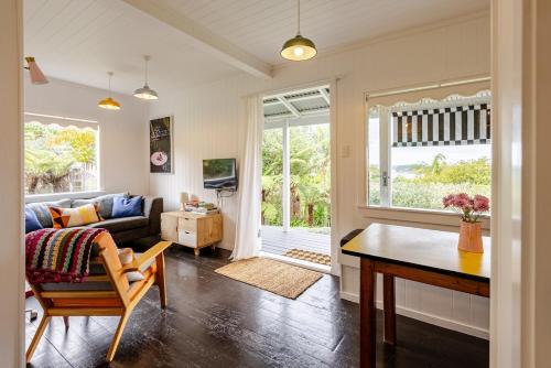 a living room with a couch and a table at Rosies cottage hideaway in Stanmore Bay with lovely seaview in Whangaparaoa
