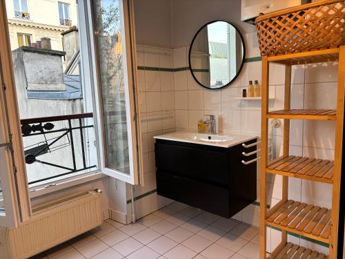 une salle de bain avec un lavabo, un miroir et une fenêtre dans l'établissement Charming Parisian loft near Opera - TF24, à Paris