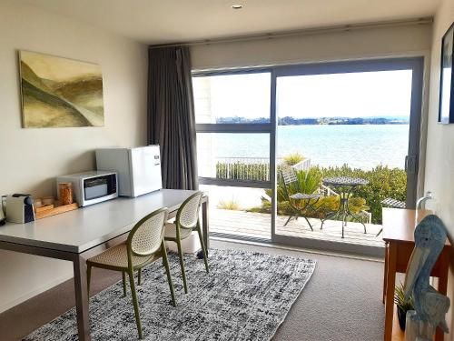 a living room with a table and chairs and a large window at Once Upon a Tide in Auckland