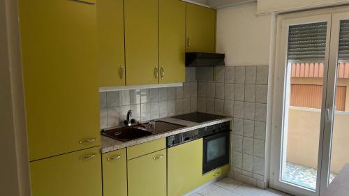 a kitchen with yellow cabinets and a sink at Bel appartement lumineux Monthey Gare deux pièces & cuisine séparée in Monthey