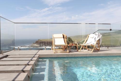 two chairs and a table next to a swimming pool at Coastal Indulgence Water Views Romantic Coastal Beach Getaway Kiama in Kiama