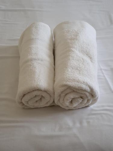 two rolls of white towels sitting on a bed at Faranie Guesthouse in Oudtshoorn