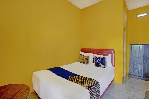 a bedroom with a bed with yellow walls at Hotel O Anisah Adil Homestay SyariahNearsmart Kampung Desa Pakistaji in Banyuwangi