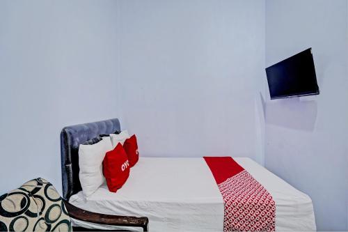 a bedroom with a bed and a tv on a wall at Hotel O Niza Guesthouse Syariah in Banyuwangi