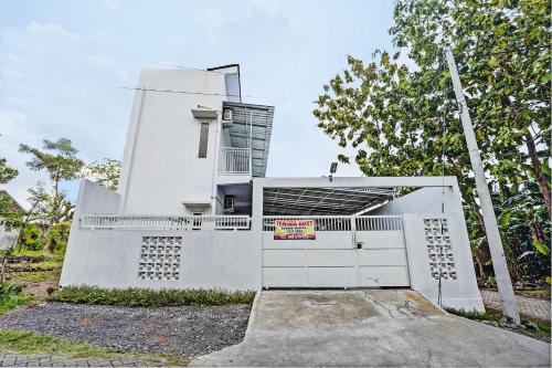 a white house with a gate in front of it at Hotel O Niza Guesthouse Syariah in Banyuwangi