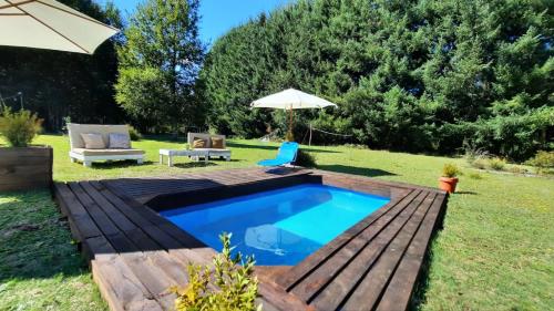 een zwembad in een tuin met een parasol bij Lafken Lodge in Villarrica