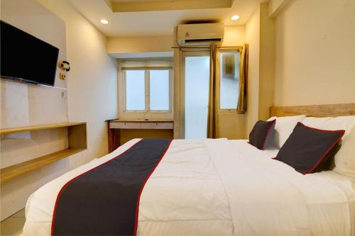 a bedroom with a large white bed with a flat screen tv at Collection O 92870 Apartement Grand Sentraland Karawang By Ipul in Karawang