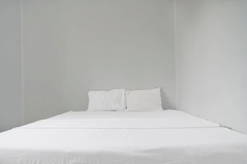 a white bed with white sheets and pillows at Hotel O Home Stay Syariah Aom Kusman in Sukabumi