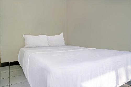 a large white bed with white sheets and pillows at Hotel O Home Stay Syariah Aom Kusman in Sukabumi