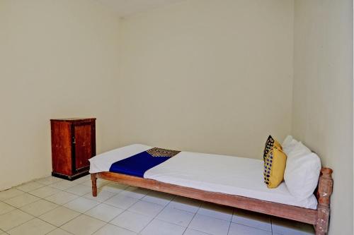 a bed with white sheets and yellow pillows in a room at Hotel O Sunyoto Homestay Syariah in Mojokerto