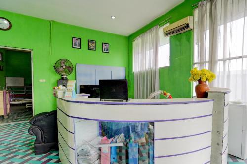 a green room with a desk with a laptop on it at Hotel O Homestay Kedamean in Gresik