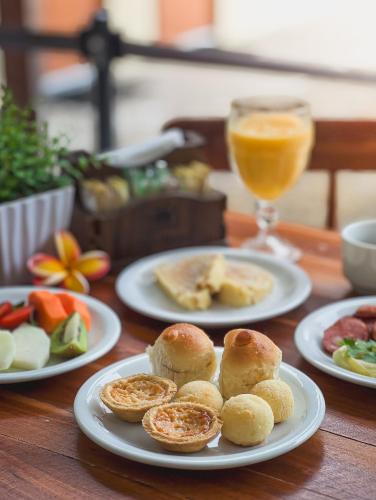 ein Tisch mit Tellern voller Essen und einem Glas Orangensaft in der Unterkunft Pousada Porto Verano in Porto De Galinhas