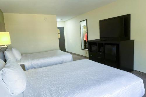 a hotel room with two beds and a flat screen tv at OYO Hotel Rome West GA in Rome