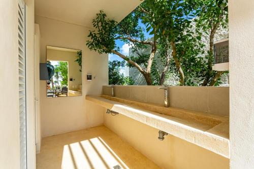 a bathroom with a mirror and a window with trees at Luxurious penthouse by the beach in Akumal