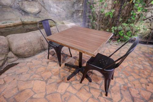 une table et une chaise en bois installées sur une terrasse en pierre dans l'établissement Hotel O Backpaker Seraya, à Nagoya