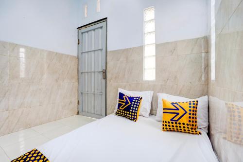 a bedroom with a white bed with yellow and blue pillows at Hotel O Karman's Sari Homestay Syariah in Gresik
