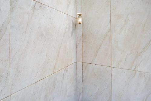 a white tiled wall with a light on it at Hotel O Karman's Sari Homestay Syariah in Gresik