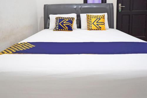 a bed with two blue and yellow pillows on it at Hotel O Kost Putih Syariah in Blitar