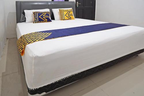 a large bed with yellow and blue pillows on it at Hotel O Kost Putih Syariah in Blitar