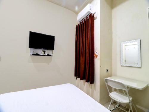 a room with a bed and a desk and a tv at OYO Life 92707 D-akomiba Residence in Jambi