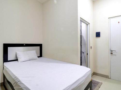 a bedroom with a white bed with a black headboard at OYO Life 92707 D-akomiba Residence in Jambi