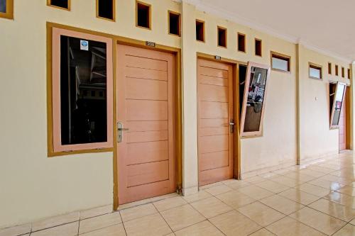 two orange doors in a room with a tile floor at OYO Life 92663 Karmel 6 in Purwokerto