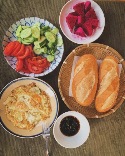 a table topped with plates of food with bread and vegetables at LoiLoi's Home - Mui Ne in Mui Ne