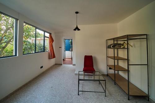 a room with a glass shelf and a red chair at Apartamento nuevo con vistas a jardín cerca de Coyoacán in Mexico City
