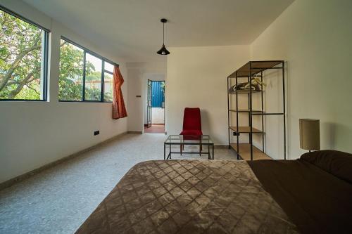 a bedroom with a bed and a red chair at Apartamento nuevo con vistas a jardín cerca de Coyoacán in Mexico City