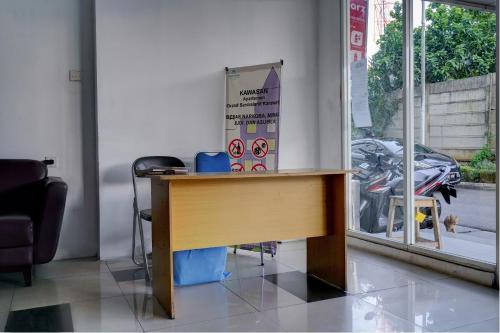 a wooden desk in a room with a motorcycle outside a window at OYO Life 92889 Apartement Grand Sentraland Karawang By A.t Room in Karawang