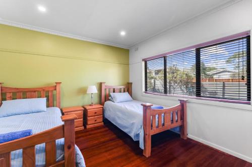 two beds in a room with two windows at Red Gum Beach Retreat in Cowes