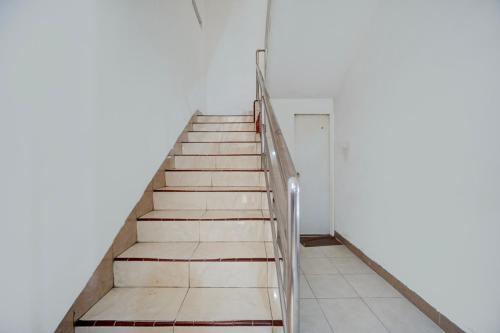 a staircase leading up to a white room with a door at OYO Life 93083 Nova Jaya 3 Homestay Syariah in Lamongan