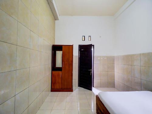 a room with a door and a bed and a shower at OYO Life 92841 Kos 88 in Negara