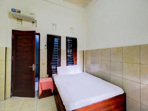 a small bedroom with a white bed and a door at OYO Life 92841 Kos 88 in Negara
