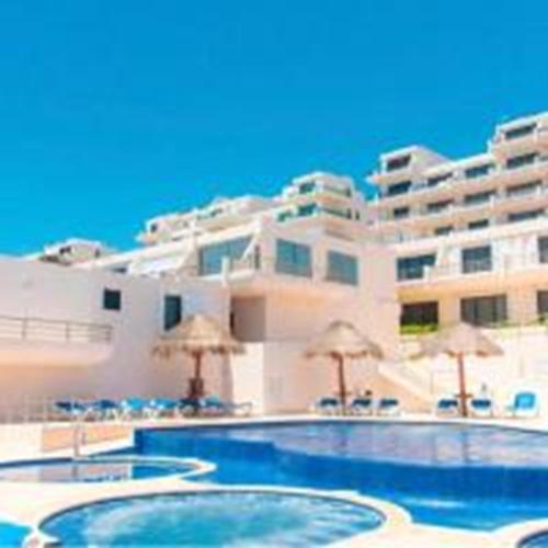 a hotel with a swimming pool with umbrellas and a building at Ocean view condo with balcony hotel zone Cancun in Cancún