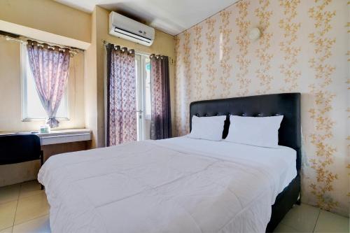 カラワンにあるOYO Life 92874 Apartement Grand Sentraland Karawang By Red Dragonの花柄の壁紙を用いた白い大型ベッド付きのベッドルーム1室