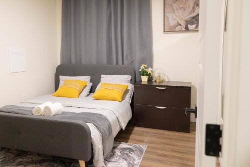 a bedroom with a bed with two yellow pillows at Modern and Private Guest Suite in Regina, SK in Regina