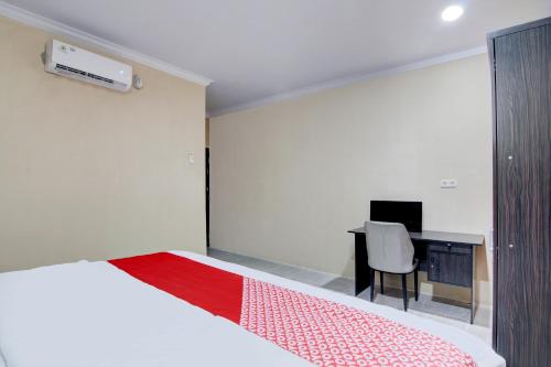 a bedroom with a bed and a desk with a computer at OYO 93087 Wisma Apel Syariah in Parit