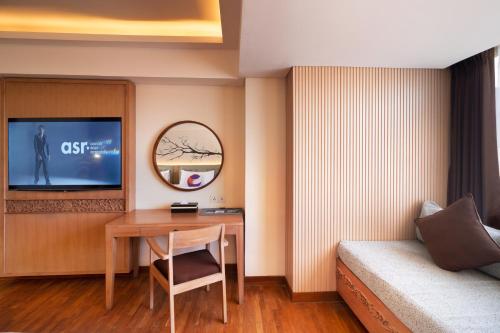 a room with a desk and a bed and a mirror at FOX Hotel Jimbaran Beach Bali in Jimbaran